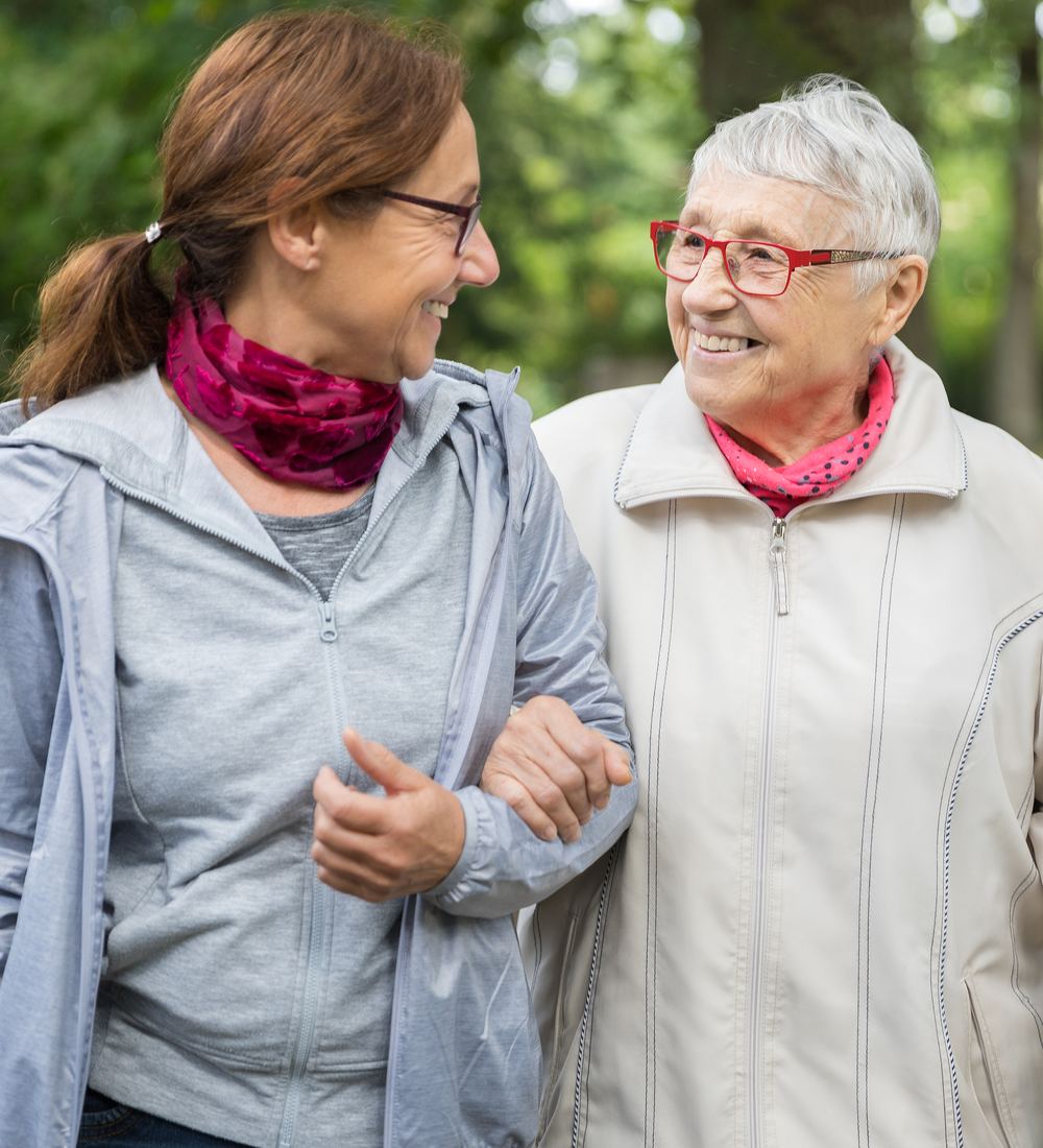 Pflegekraft und Seniorin beim gemeinsamen Spaziergang
